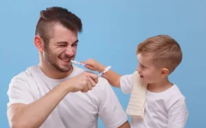 Image of dad and son toothbrushing together, on a pale blue background